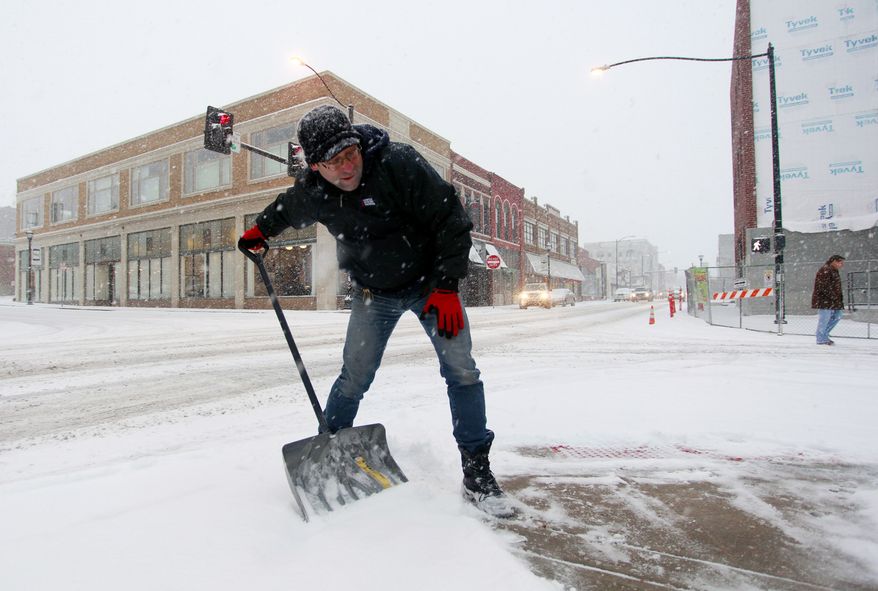 David Velasco shovels snow on a sidewalk in Springfield, Mo., on Thursday, Dec. 5, 2013. Most of southern Missouri was under winter weather warnings, with up to 8 inches of snow possible by Friday evening. (AP Photo/The Springfield News-Leader, Nathan Papes) NO SALES