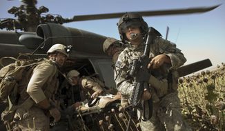 US Army flight medic SPC. Daniel Miller, right, stands guard as United States Marines place a colleague wounded in an IED strike into a waiting medevac helicopter from the US Army&#39;s Task Force Lift &quot;Dust Off&quot;, Charlie Company 1-214 Aviation Regiment at a &quot;hot&quot; landing zone in Sangin, in the volatile Helmand Province of southern Afghanistan, Friday, May 13, 2011. (AP Photo/Kevin Frayer)