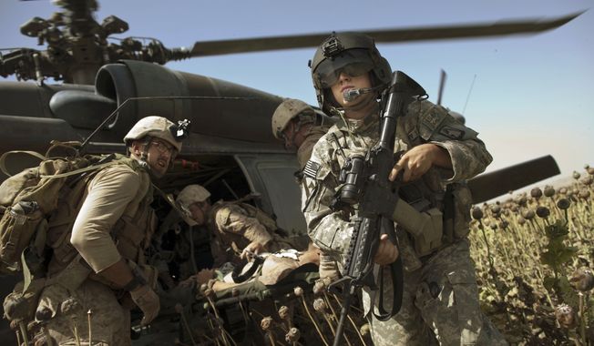 US Army flight medic SPC. Daniel Miller, right, stands guard as United States Marines place a colleague wounded in an IED strike into a waiting medevac helicopter from the US Army&#x27;s Task Force Lift &quot;Dust Off&quot;, Charlie Company 1-214 Aviation Regiment at a &quot;hot&quot; landing zone in Sangin, in the volatile Helmand Province of southern Afghanistan, Friday, May 13, 2011. (AP Photo/Kevin Frayer)