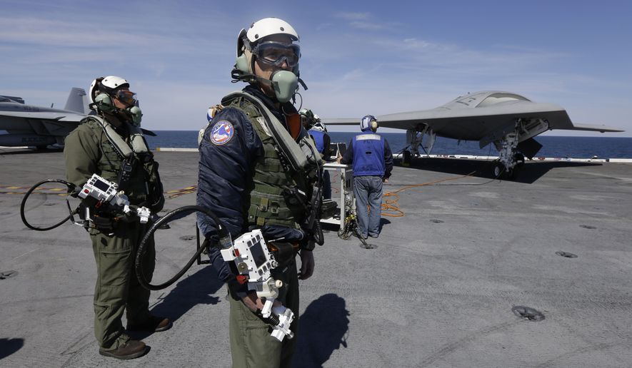**FILE** Northrop Grumman test pilots Dave Lorenz (right) and Bruce McFadden prepare to taxi the Navy X-47B drone to be launched off the nuclear powered aircraft carrier USS George H. W. Bush off the coast of Virginia on May 14, 2013. (Associated Press)