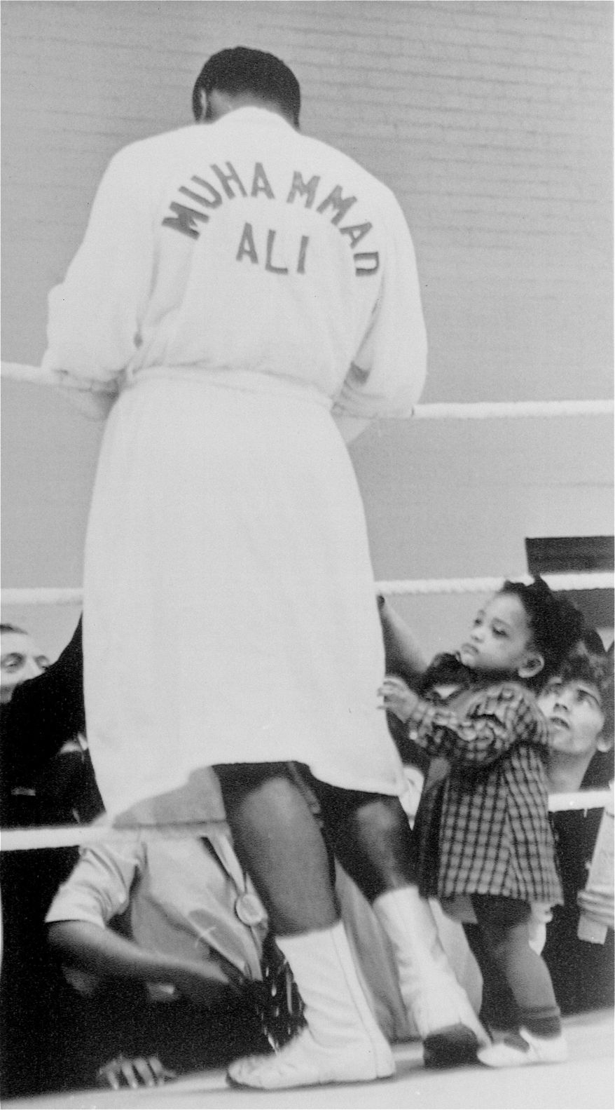 Two year old Shelley Obermuller tugs for the attention of Cassius Clay as the world heavyweight champion gives autographs to admirers during a training session in London, England, May 17, 1966.  Clay, who calls himself Muhammad Ali, will defend his title against British heavyweight king Henry Cooper when they meet in the British capital in a title bout May 21.  (AP Photo)