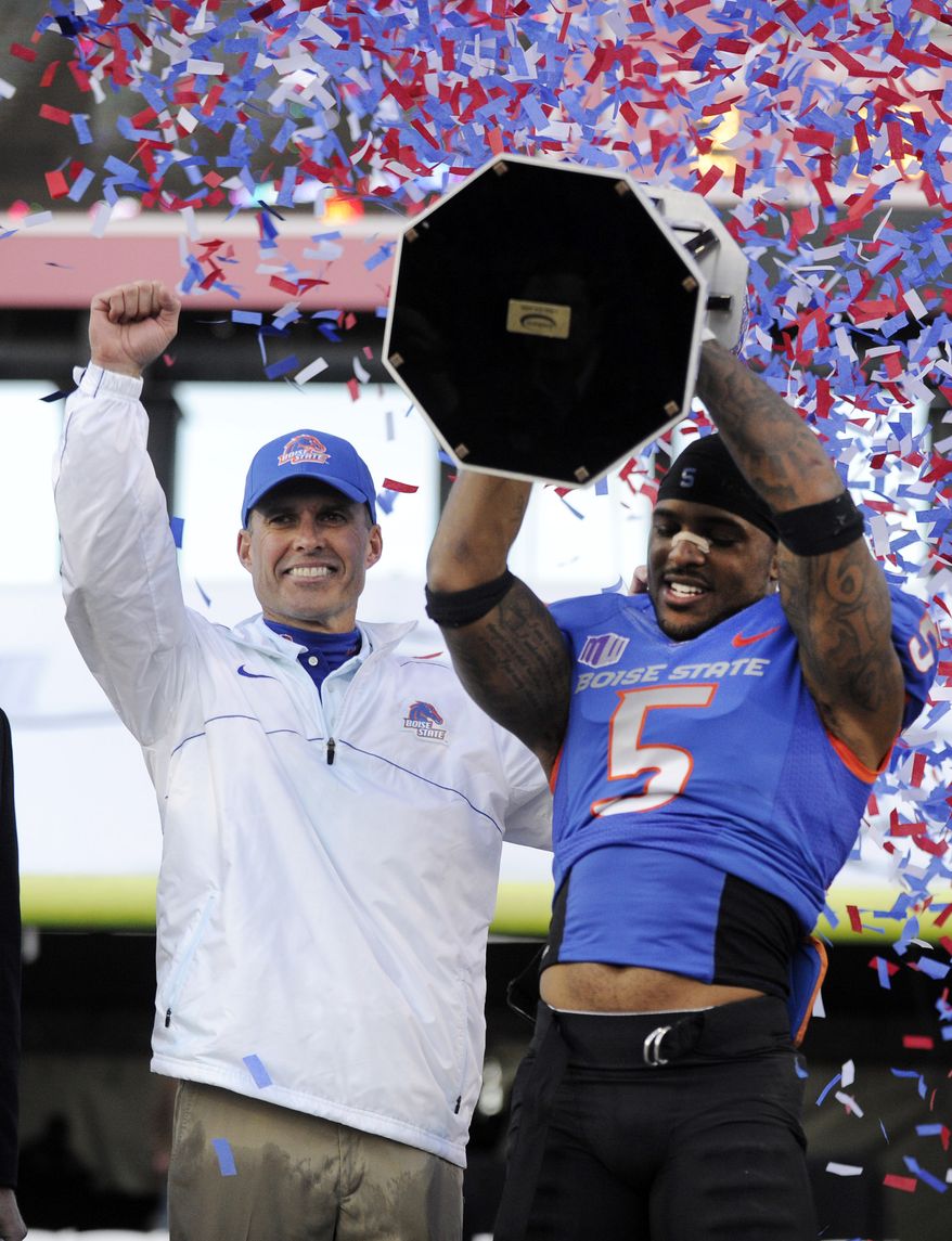 FILE - In this Dec. 22, 2012 file photo, Boise State coach Chris Peterson, left, gestures as cornerback Jamar Taylor holds the championship trophy after the MAACO Bowl NCAA college football game against Washington, in Las Vegas. A person familiar with the decision tells The Associated Press that Petersen has agreed to leave Boise State and be the football coach at Washington. The person told spoke on the condition of anonymity Friday morning, Dec. 6, 2013, because the hiring had not been announced by Washington. (AP Photo/David Becker)
