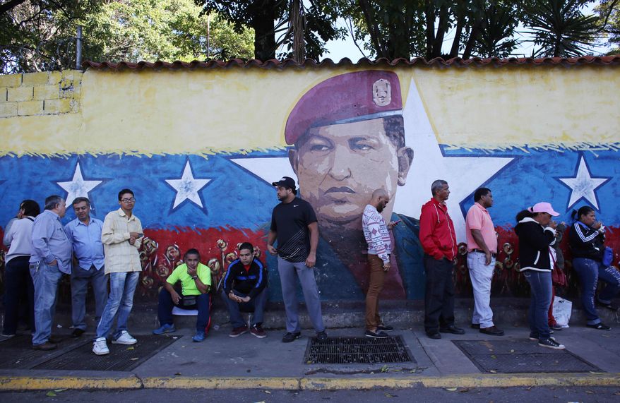 Residents wait in line to enter a polling station to vote in front of a wall painting depicting late president Hugo Chavez during municipal elections in Caracas, Venezuela, Sunday, Dec. 8, 2013. Venezuelans head to the polls to elect mayors and city councilors at a moment when the country's economic troubles have deepened, with inflation touching a two-decade high of 54 percent, and shortages of everything from toilet paper to milk spreading while the black market value of the currency plunges. (AP Photo/Ariana Cubillos)