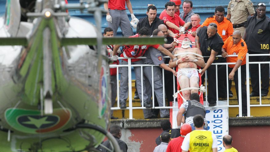An injured fan is carried on a stretcher after clashes with team fans during a Brazilian league soccer match between Atletico Paranaense and Vasco da Gama in Joinville, southern Brazil, Sunday, Dec. 8, 2013. A key Brazilian league match was stopped Sunday after fans started fighting in the stands and a helicopter had to land on the pitch to airlift a seriously injured man. A doctor said two other fans were hospitalized in serious condition and one was treated for a minor injury at the stadium. (AP Photo/Carlos Moraes, Agencia O Dia)