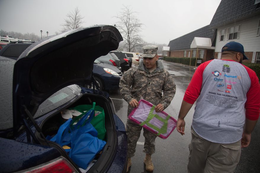 GRATITUDE: Army Spc. Roberto Rodriguez thanks a volunteer for helping him carry bags of food and supplies he received from Operation Homefront on Monday.