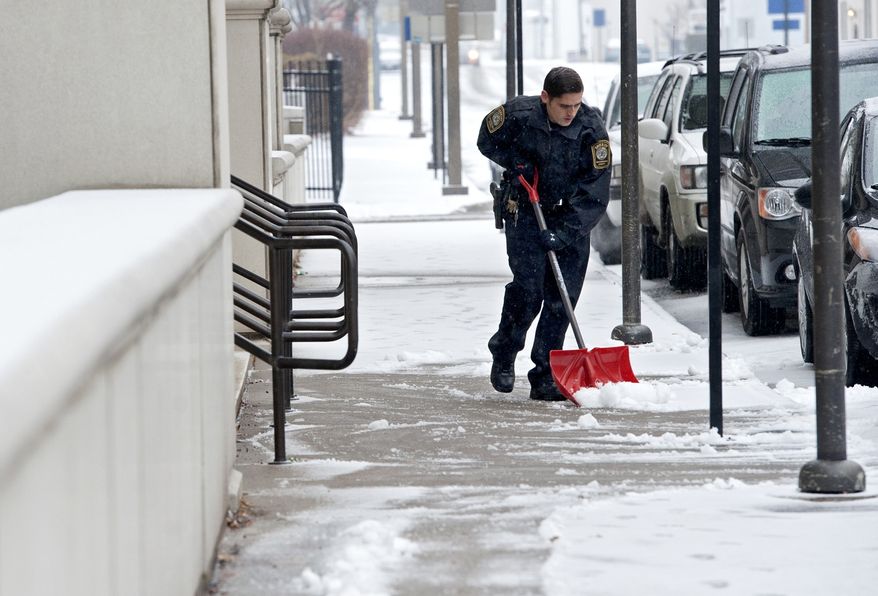 Corporal Cory Madison with the Rockingham County Sheriffs Department, shovels off snow and ice from in front of the Rockingham-Harrisonburg Judicial Center on Sunday, Dec. 8, 2013 in Harrisonburg, Va. More than 89,000 customers in Virginia are without electricity as a winter storm moves across the state. (AP Photo/Daily News-Record, Jason Lenhart)