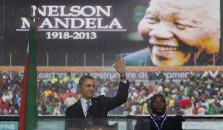 In this Dec. 10, 2013, photo, President Barack Obama waves as he arrives to speak at the memorial service for former South African president Nelson Mandela at the FNB Stadium in the Johannesburg, South Africa township of Soweto. (AP Photo/Evan Vucci)