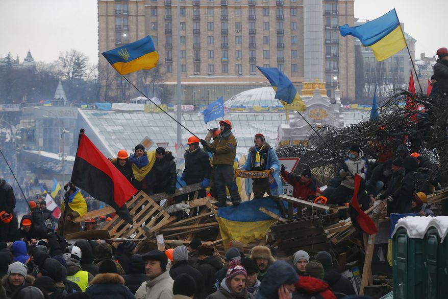 Pro-European Union activists wave flags celebrating riot police leaving form the Independence Square in Kiev, Ukraine, Wednesday, Dec. 11, 2013. Security forces clashed with protesters as they began tearing down opposition barricades and tents set up in the center of the Ukrainian capital early Wednesday, in an escalation of the weeks-long standoff threatening the leadership of President Viktor Yanukovych. (AP Photo/Sergei Grits)