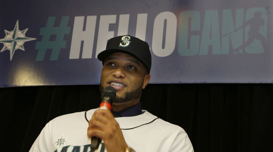 Robinson Cano sits under a sign that reads "#HelloCano" as he talks to fans gathered at an event to honor him as the newest member of the Seattle Mariners baseball team on Thursday, Dec. 12, 2013, in Seattle. (AP Photo/Ted S. Warren)