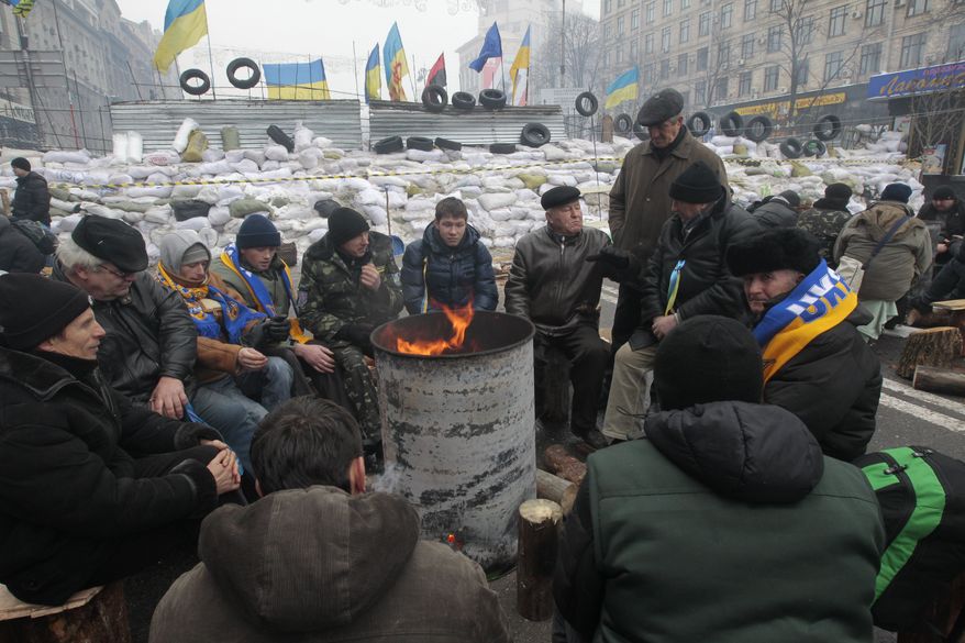 Pro-European Union activists warm themselves in front of barricades at their tent camp in Independence Square in Kiev on Wednesday, Dec. 11, 2013. Ukraine was thrown into crisis last month when President Viktor Yanukovych suddenly backed away from a long-awaited political and economic agreement with the European Union, deciding to focus instead on restoring trade ties with Russia.  (AP Photo/Sergei Chuzavkov)