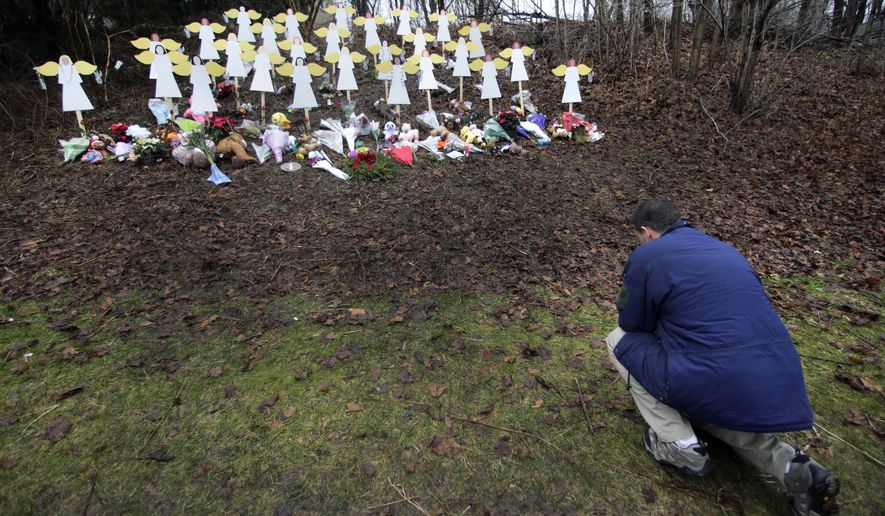FILE - In this Dec. 18, 2012 file photo, Robert Soltis, of Newtown, Conn., pauses after making the sign of the cross at a memorial to Sandy Hook Elementary School shooting victims in Newtown. Adam Lanza walked into the school on Dec. 14, 2012, and opened fire, killing 26 people, including 20 children, before killing himself. (AP Photo/Charles Krupa, File)