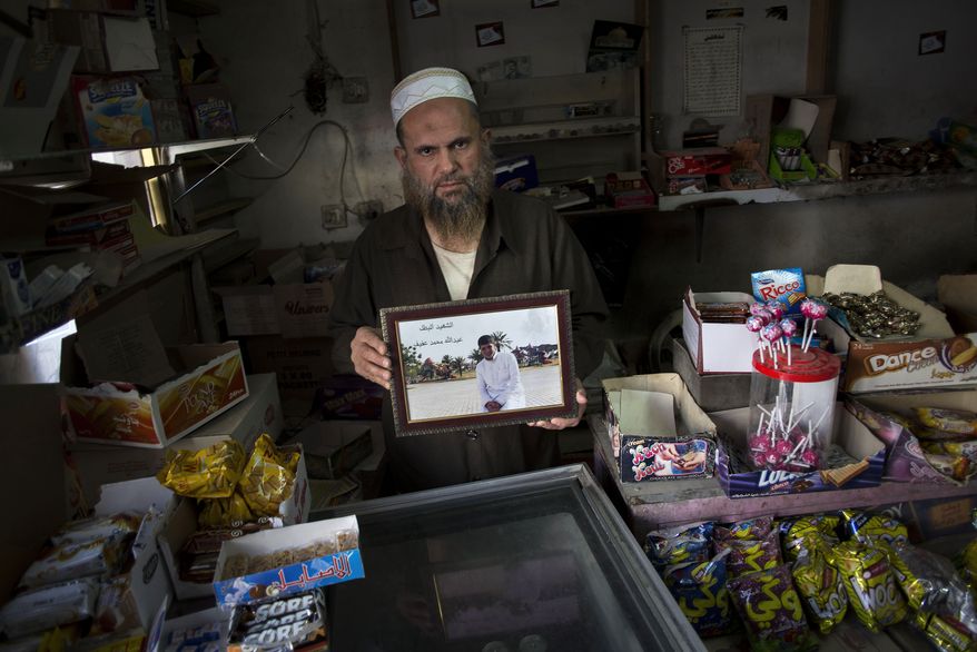 In this Friday, Oct. 25, 2013 photo, Mohammed Siddeh, 52, at his workshop in Russeifa, outside Amman, Jordan, holds a picture of his son, Abdullah Siddeh, with the boy's name inscribed on the print in Arabic. On his last day as an ordinary teenager, Abdullah kept to his daily routine: He filled in for his father at the small family grocery in the afternoon, asked his mother at home about dinner and then played soccer with friends at the nearby high school. After the game, the 17-year-old slipped out of his hometown in central Jordan. Six months later, Mohammed got a phone call from Syria. His son had blown himself up in a rebel attack on a police station in Syrian capital of Damascus, the unknown man on the line told him. Mohammed said he asked the man how he could bring his son’s remains home for burial. The reply: "There is no body." (AP Photo/Manu Brabo)