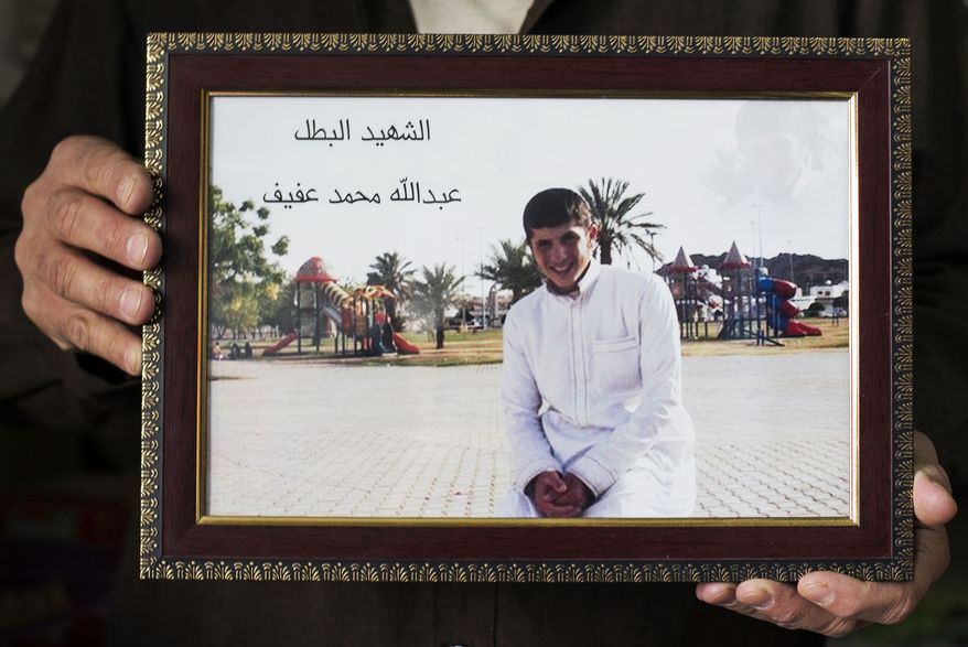 In this Friday, Oct. 25, 2013 photo, Mohammed Siddeh, 52, at his workshop in Russeifa, outside Amman, Jordan, holds a picture of his son, Abdullah Siddeh, with the boy's name inscribed on the print in Arabic. Abdullah blew himself up in a rebel attack on a police station in Syrian capital of Damascus at the age of 17. Abdullah left his home in December, 2012, without telling his parents. He surfaced in Syria a few days later, where he joined Jabhat al-Nusra. (AP Photo/Manu Brabo)