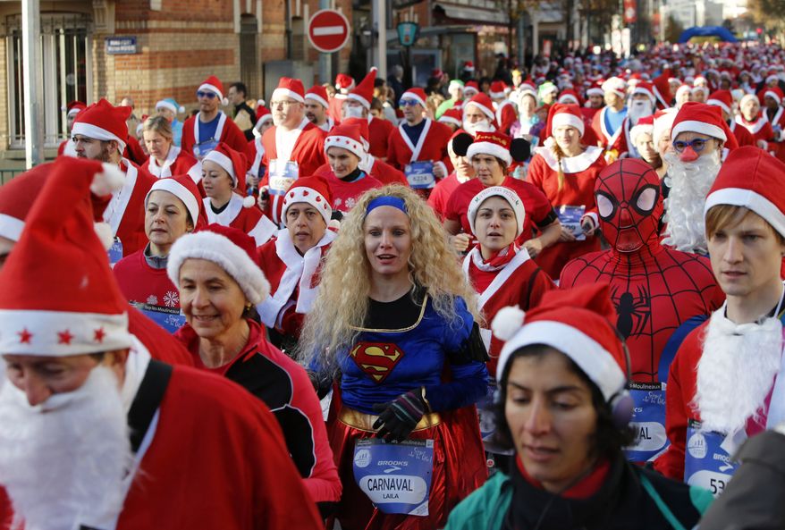 Runners, dressed as Santa Claus, and one dressed as Superwoman, take part in the 37th "Christmas Corrida Race" in the streets of Issy Les Moulineaux, on the western outskirts of Paris, Sunday, Dec. 15, 2013. (AP Photo/Francois Mori)