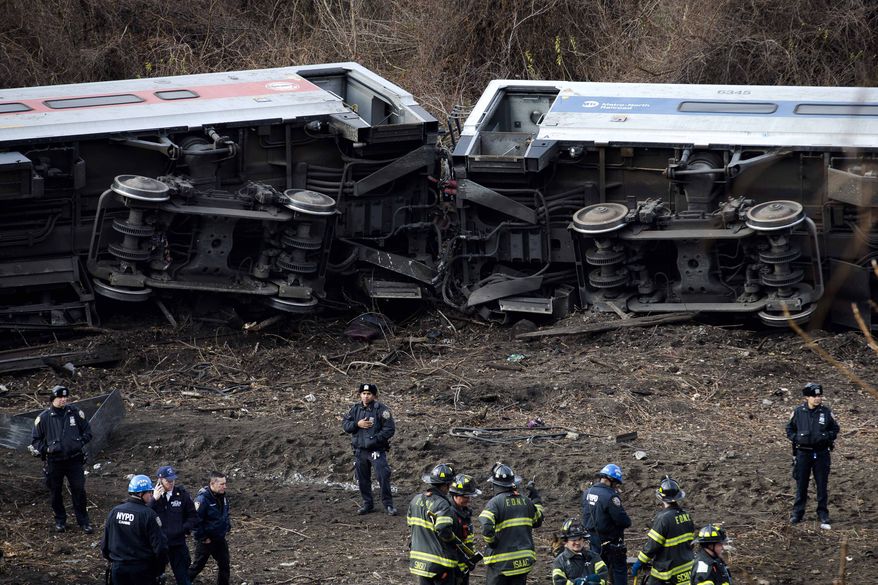 FILE- In this Dec. 1, 2013 file photo, emergency personnel respond to the scene of a Metro-North passenger train derailment in the Bronx borough of New York. Metro-North trains are equipped with an automatic breaking system that might have prevented the crash, but the system was in place to regulate the distance between trains, not to control speeds as trains approached curves, or passed over hills and bridges. Since the crash, the speed limit was lowered on the approach to the curve, plus an alarm will sound and an automatic braking system will engage is a train approaches the bend too fast. (AP Photo/John Minchillo, File)