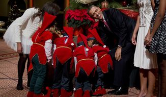 President Barack Obama, laughs as children dressed like elves gathered around a Christmas tree, look at their presents presented to them by the first family at the National Building Museum in Washington, Sunday, Dec. 15, 2013. The first family is attending the taping of the annual 2013 Christmas in Washington, celebrating its 32nd year anniversary. On the left is the president&#39;s daughter Malia Obama. (AP Photo/Manuel Balce Ceneta)