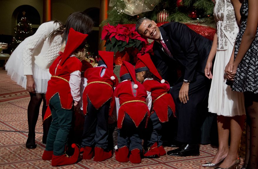 President Barack Obama, laughs as children dressed like elves gathered around a Christmas tree, look at their presents presented to them by the first family at the National Building Museum in Washington, Sunday, Dec. 15, 2013. The first family is attending the taping of the annual 2013 Christmas in Washington, celebrating its 32nd year anniversary. On the left is the president's daughter Malia Obama. (AP Photo/Manuel Balce Ceneta)