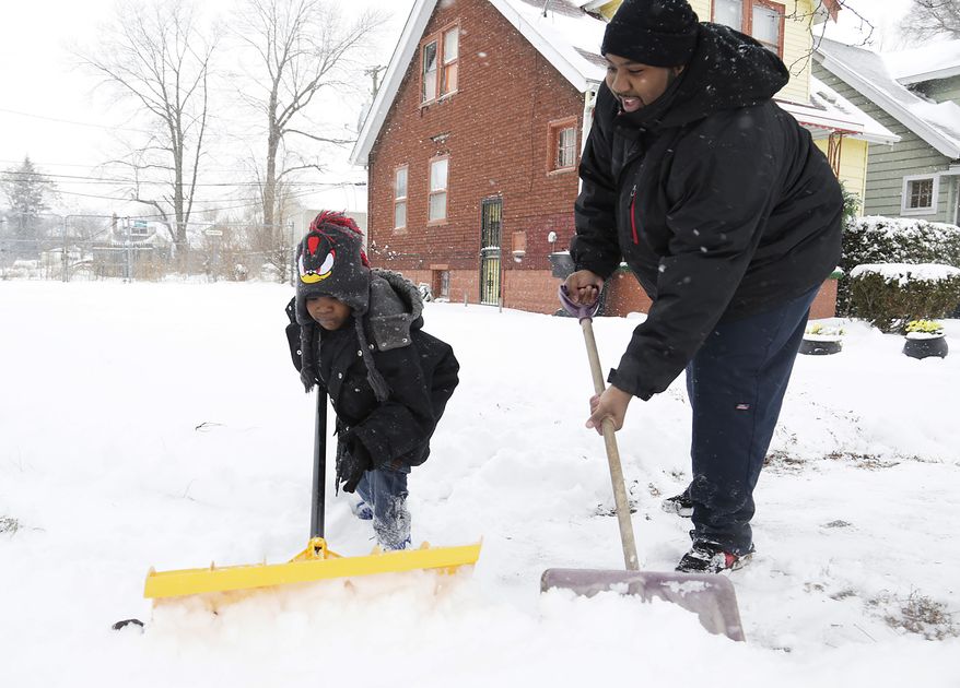 Keishard Hatcher (left), 6, helps his father, Montez Gates, shovel in front of their Monica Street home in Detroit after heavy snows covered the area on Sunday, Dec. 15, 2013. A pre-winter snowstorm continues to grip parts of Michigan, with accumulations already topping 9 inches in the state's southeastern corner. (AP Photo/Detroit Free Press, Mandi Wright)