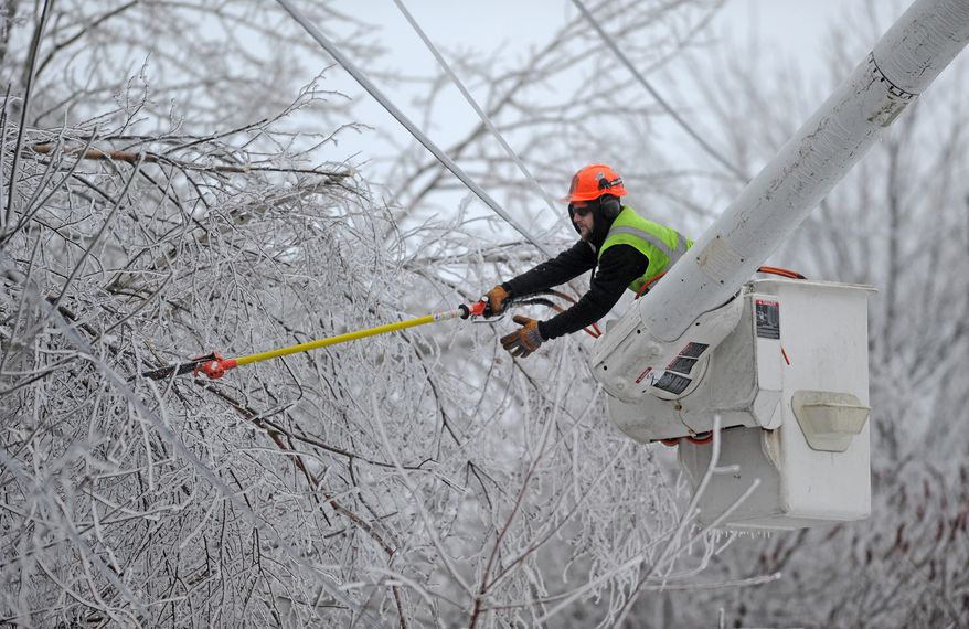Andrew Powers, an arborist with Asplundh Tree Experts, clears power lines from iced branches along Mayflower Heights Drive in Waterville, Maine, on Monday, Dec. 23, 2013. (AP Photo/The Central Maine Morning Sentinel, Michael G. Seamans)