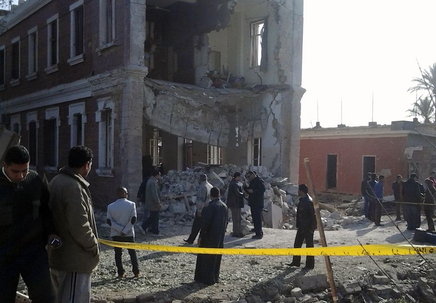 **FILE** Security personnel and others inspect the site of an explosion outside a military intelligence building in Anshas, a rural village in Sharqiya province, nearly 50 kilometers (30 miles) northeast of Cairo, on Dec. 29, 2013. Attacks on security targets have become frequent following the July 3 ouster of Islamist President Mohammed Morsi. (Associated Press)