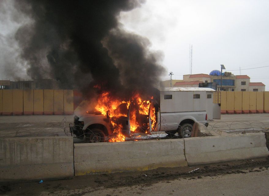 ** FILE ** A police truck full of prisoners being transported was set afire by al Qaeda fighters after they freed prisoners in front of the main provincial government building, in Fallujah, 40 miles (65 kilometers) west of Baghdad, Iraq, Wednesday, Jan. 1, 2014. (AP Photo)