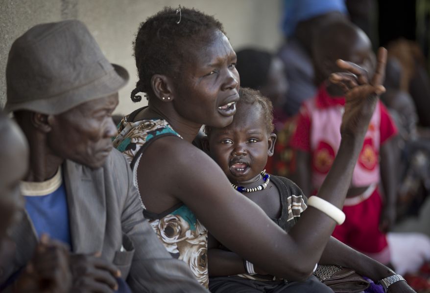 Displaced people who fled from recent fighting in Bor queue outside a clinic run by Medecins Sans Frontieres (Doctors Without Borders) set up in a school building in the town of Awerial, South Sudan Thursday, Jan. 2, 2014. The international Red Cross said Wednesday that the road from Bor to the nearby Awerial area "is lined with thousands of people" waiting for boats so they could cross the Nile River and that the gathering of displaced is "is the largest single identified concentration of displaced people in the country so far". (AP Photo/Ben Curtis)
