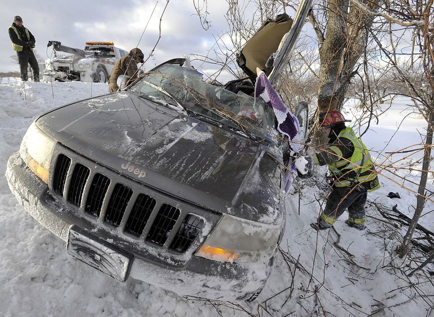 Tow operators work to salvage a wrecked Jeep as Fuller Hose Co. Lt. Chris Skrekla, right, searches for the vehicle identification number after two people were injured in a rollover accident on westbound Interstate 90 just west of the Bort Road overpass in North East Township, near Erie, Pa. on Friday, Jan. 3, 2014. Pennsylvania State Police responded to numerous accidents in the area early Friday due to wintry weather. (AP Photo/Erie Times-News, Greg Wohlford) TV OUT; MAGS OUT