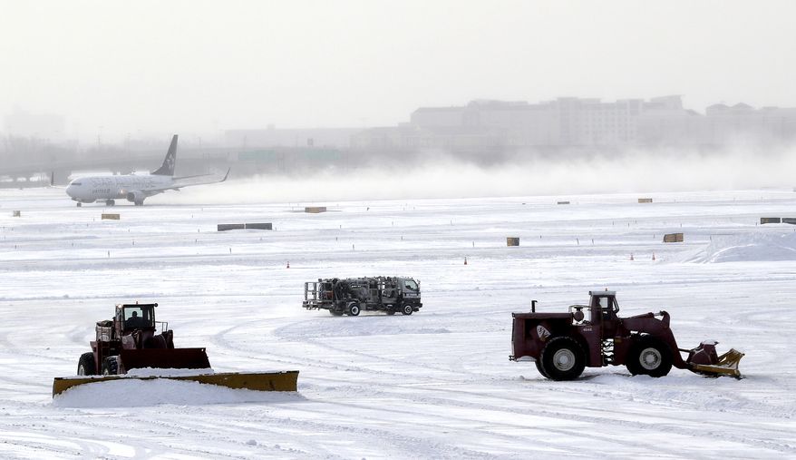 A plane takes off from Newark Liberty International Airport as workers plow the tarmac, Friday, Jan. 3, 2014, in Newark, N.J. New Jersey Gov. Chris Christie declared state of emergency Thursday, urging residents to stay home. Schools were closed as temperatures reached below 20 degrees with wind-chills below zero in some places. (AP Photo/Julio Cortez)