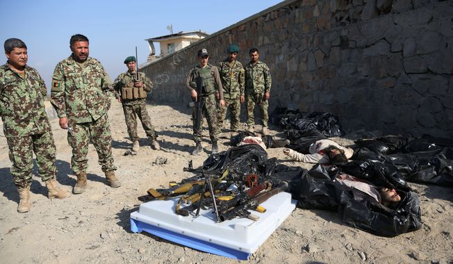 Afghan officials standing by bodies of Taliban fighters investigate the site of a deadly suicide attack on a joint NATO-Afghan base in Nangarhar province, east of Jalalabad, Afghanistan, Saturday, Jan. 4, 2014. NATO said a service member died following a suicide bombing in eastern Afghanistan, without identifying the soldier&#x27;s nationality. An official said five Taliban fighters on foot tried to storm the base after the bombing, but Afghan and NATO troops returned fire, killing the attackers. (AP Photo/Rahmat Gul)