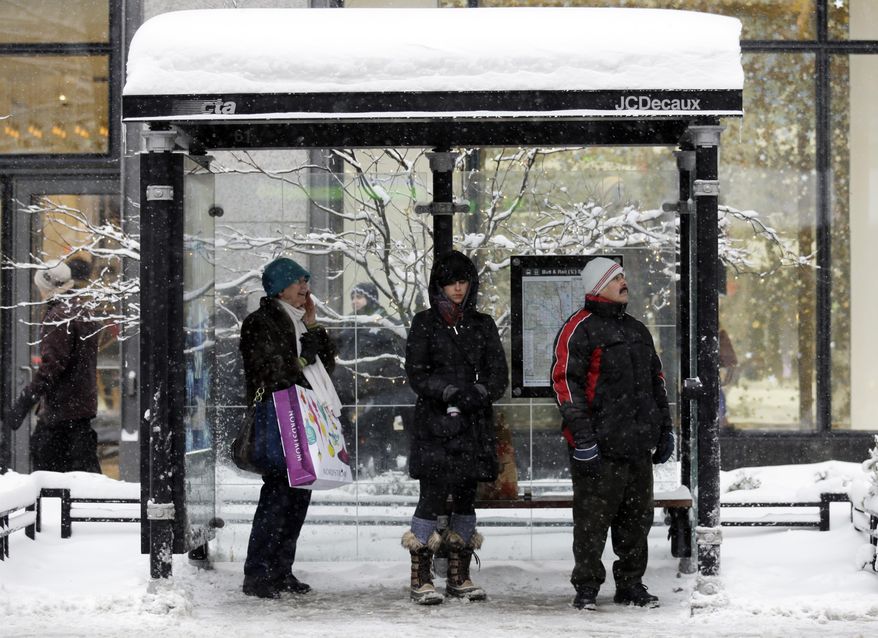 People wait for a bus at a bus stop in downtown Chicago on Sunday, Jan. 5, 2014. Sunday night temperatures will drastically drop to about minus 20 degrees. (AP Photo/Nam Y. Huh)