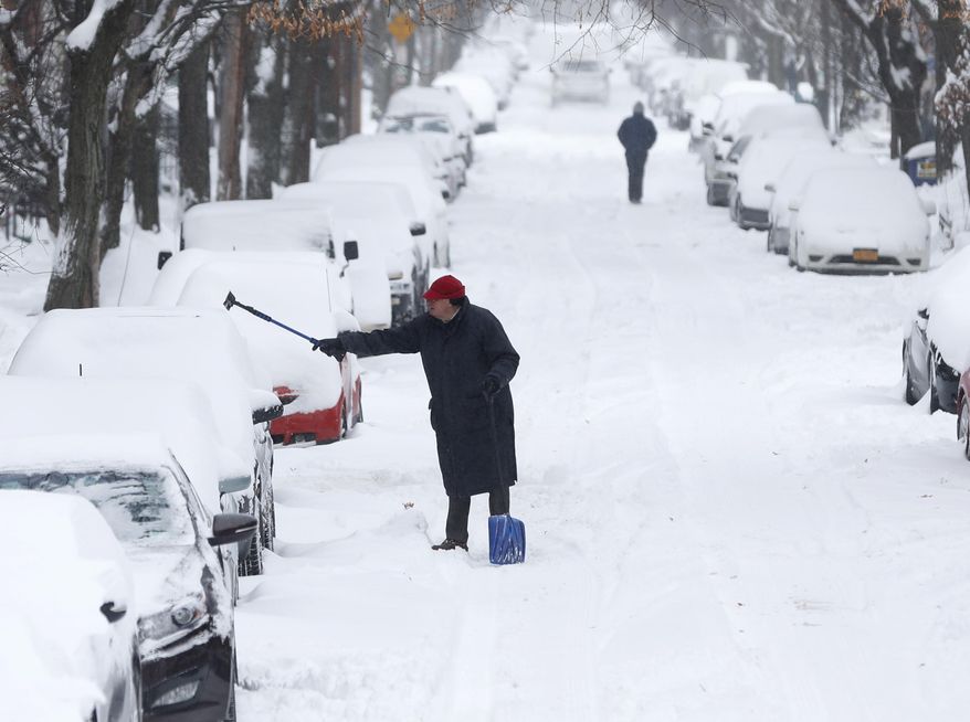A man clears snow from a vehicle on Friday, Jan. 3, 2014, in Albany, N.Y. A winter storm slammed into the U.S. Northeast with howling winds and frigid cold, dumping nearly two feet (60 centimeters) of snow in some parts and whipping up blizzard-like conditions Friday. (AP Photo/Mike Groll)