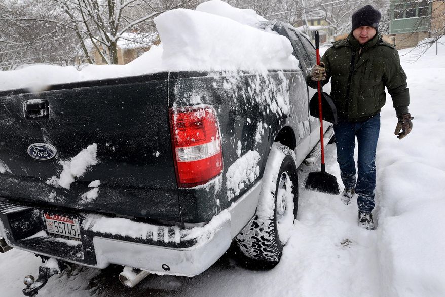 David Paluch brushes off snow from his truck in front of his home in Barrington, Ill., Thursday, Jan. 2, 2014. The New Year's Day snow storm stretched into Thursday for parts of Illinois, bringing double-digit snow totals to the suburbs of Chicago. (AP Photo/Daily Herald, Bob Chwedyk) MANDATORY CREDIT; MAGS OUT; TV OUT