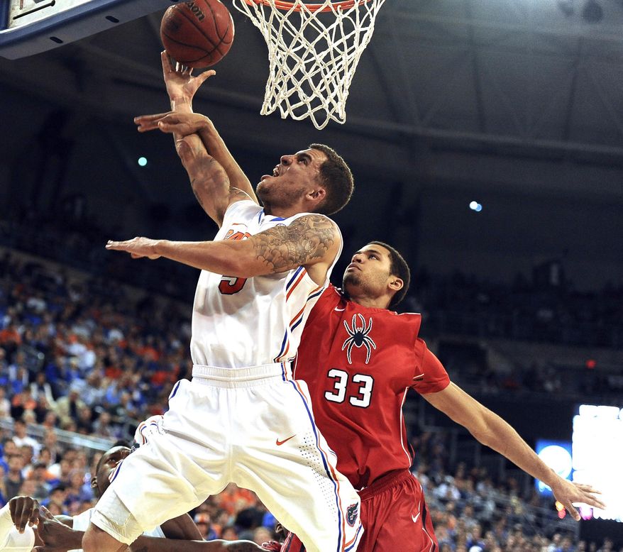 Florida's Scottie Wilbekin (5) shoots as Richmonds' Alonzo Nelson-Ododa defends during the first half of an NCAA college basketball game in Gainesville, Fla., Saturday, Jan. 4, 2014. (AP Photo/Phil Sandlin)
