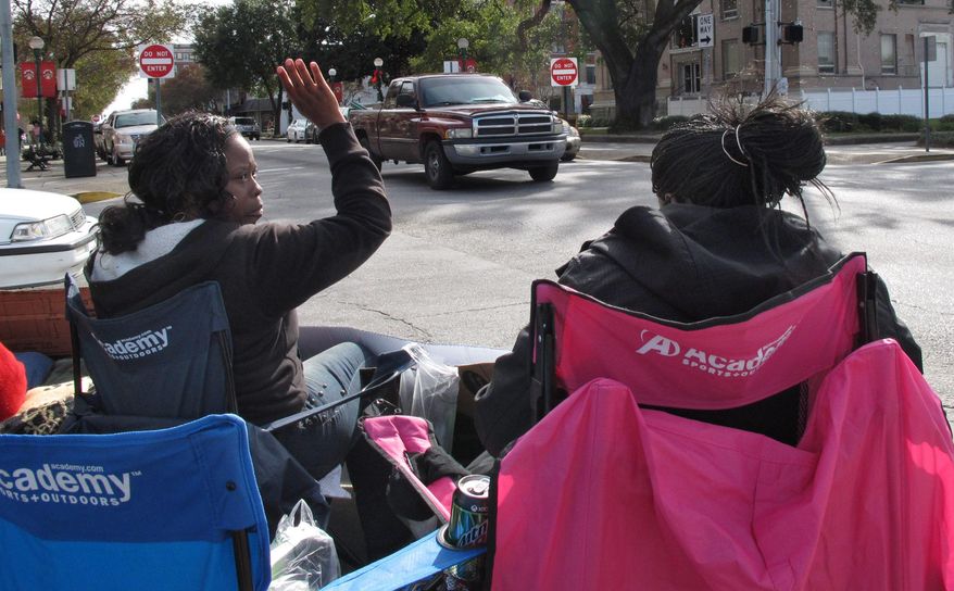Keisha Moore, an aunt of 17-year-old Kendrick Johnson, waves at passing traffic as she sits with the teenager's mother, Jacquelyn Johnson, outside the Lowndes County courthouse in Valdosta, Ga., on Dec. 13, 2013. Kendrick Johnson was found dead inside a rolled-up wrestling mat on Jan. 11, 2013, and his family has rejected investigators' conclusion that he died in an accident. The teenagers' parents and relatives have been camping out with protest signs outside the courthouse every weekday for months. (AP Photo/Russ Bynum)