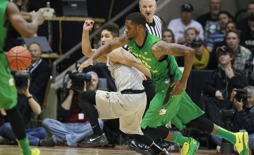 Oregon forward Elgin Cook, front, pursues the loose ball with Colorado guard Askia Booker in the first half of an NCAA college basketball game, Sunday, Jan. 5, 2014, in Boulder, Colo. (AP Photo/David Zalubowski)