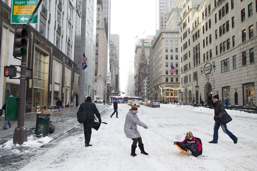 Liam Necina is pulled along in a snow sled on 58th Street by his mother Noreen, Friday, Jan. 3, 2014, in New York. New York City public schools were closed Friday after up to 7 inches of snow fell by morning in the first snowstorm of the winter. (AP Photo/John Minchillo)