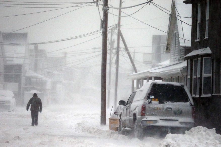 A man walks in the snow down a road along the shore in Scituate, Mass., Friday, Jan. 3, 2014. A winter storm slammed into the U.S. Northeast with howling winds and frigid cold, dumping nearly 2 feet (60 centimeters) of snow in some parts and whipping up blizzard-like conditions Friday. (AP Photo/Michael Dwyer)