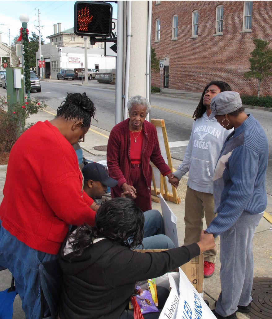 Elsie Williams, center, Jarius Humprey, second right, and Yvette Humphrey, right, pray with relatives of 17-year-old Kendrick Johnson on Dec. 13, 2013, in Valdosta, Ga. Johnson was found dead inside a rolled gym mat at his high school on Jan. 11, 2013, and authorities concluded he died in a freak accident. His family is fighting to reopen the case. (AP Photo/Russ Bynum)