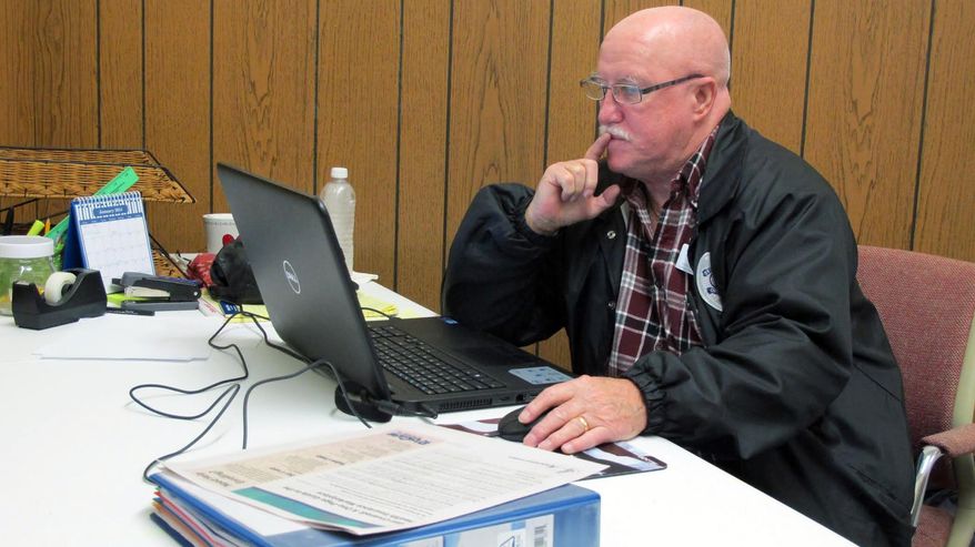 In this photo taken Tuesday, Dec. 17, 2013, Joe Manning sits in his office in De Funiak Springs, Fla. Manning is an outreach worker trained to sign people in rural Florida to participate in the Affordable Care Act. (AP Photo/Melissa Nelson)
