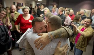 FILE - In this Dec. 20, 2013 file photo, Chris Serrano, left, and Clifton Webb embrace after being married, as people wait in line to get licenses outside of the marriage division of the Salt Lake County Clerk&#x27;s Office in Salt Lake City. The Supreme Court on Monday, Jan. 6, 2014, put same-sex marriages on hold in Utah, at least while a federal appeals court more fully considers the issue.  (AP Photo/Kim Raff, File)