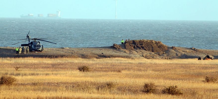 A helicopter lands near the scene of the wreckage of a US Military Air Force Pave Hawk helicopter, at right, in Salthouse, England, Wednesday Jan. 8, 2014. The Pave Hawk helicopter slammed into the eastern coast during a low-level training mission Tuesday evening. Authorities cordoned off flooded marshes Wednesday to remove the bodies of four U.S. Air Force crewmen that were killed in the crash. (AP Photo/PA, Chris Radburn)