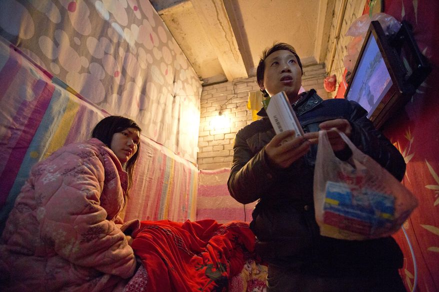 In this Jan. 4, 2014 photo, Wu Yongyuan, right, shows medicines his wife Gong Qifeng, left, takes to control her schizophrenia symptoms, in a room they rent in Beijing for stay as Wu keeps petitioning to China's central government for help. When Gong's mind is clear, she can recall how she begged for mercy. Several people pinned her head, arms, knees and ankles to a hospital bed before driving a syringe of labor-inducing drugs into her stomach. She was seven months pregnant with what would have been her second boy. The drugs caused her to have a stillborn baby after 35 hours of excruciating pain. Since the abortion more than two years ago, Gong has been diagnosed with schizophrenia. (AP Photo/Alexander F. Yuan)
