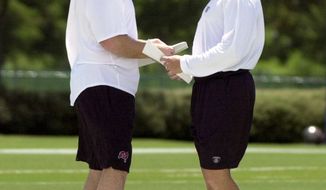 Jay Gruden, left, goes over plans with Bucs coach and brother Jon Gruden, (cq&#39;d by media guide) right, at Bucs camp at Disney&#39;s Wide World of Sports Complex Wednesday, August 14, 2002. Photo by: James Borchuck/Tampa Bay Times