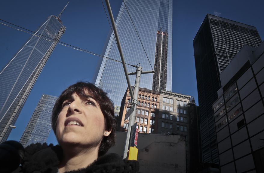 Deborah Petti, a management consultant, stands outside her home, center, a 12-story century old brownstone building, during an interview on Thursday, Jan. 9, 2014, in New York. Petti and other residents of the area, living in the shadow of the World Trade, left center, have filed a lawsuit against plans to build a security perimeter around her neighborhood, that she said would restrict street access, create congestion and health hazards, among their concerns. (AP Photo/Bebeto Matthews)