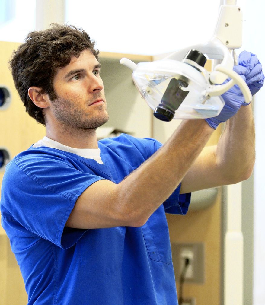 FOR RELEASE MONDAY, JANUARY 13, 2014, AT 12:01 A.M. EST - In this Monday, Dec. 16, 2013 photo, East Carolina University School of Dental Medicine student John Brune gets a light ready for a patient, in Greenville, N.C.. The school has taken the next step in its service mission by opening its pediatric dental clinic at Ledyard Ross Hall. (AP Photo/The Daily Reflector, Rhett Butler)