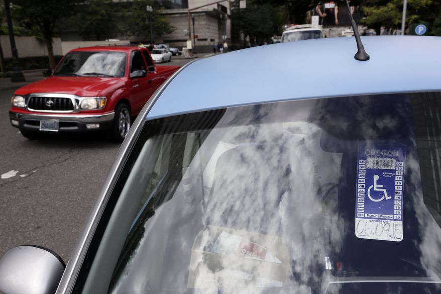 In this Sept. 3, 2013, photo, a handicapped parking tag hangs from the rearview mirror of a car parked at a metered parking spot in Portland, Ore. As the number of vehicles displaying a disabled placard has soared with an aging population and loosened eligibility standards, cities are seeing the impact in more congested downtowns and the loss of millions of dollars in revenue. (AP Photo/Don Ryan)