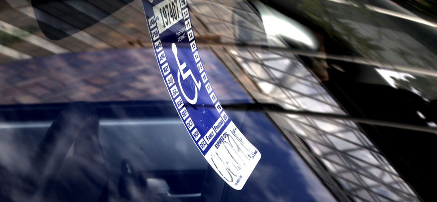 In this Sept. 3, 2013, photo, a handicapped parking tag hangs from the rearview mirror of a car parked at a metered parking spot in Portland, Ore. As the number of vehicles displaying a disabled placard has soared with an aging population and loosened eligibility standards, cities are seeing the impact in more congested downtowns and the loss of millions of dollars in revenue. (AP Photo/Don Ryan)