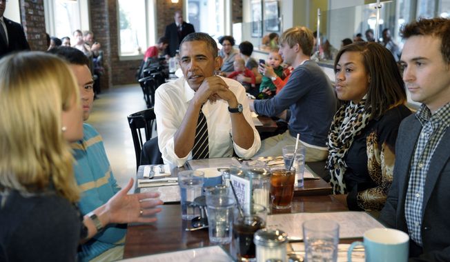 President Barack Obama listens as he has lunch with five young people at The Coupe restaurant in the Columbia Heights section of Washington, Friday, Jan. 10, 2014. The five are spearheading creative outreach efforts to connect with and help enroll young consumers through the Marketplaces or are interested in getting more involved with these efforts. Seated at the table with Obama are, from left, Anne Johnson, Andres Cruz, Obama, Jasmine Hicks, and Tommy McFly.(AP Photo/Susan Walsh)