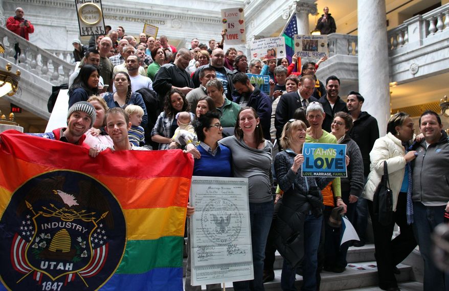 Davida Wegner, center left, and Molly Ryan Butterworth, center right, hold an enlarged copy of their recent marriage license during a rally at the Utah State Capitol in support of gay marriage Friday Jan. 10, 2014 in Salt Lake City. Supporters of gay marriage fill the rotunda as they gathered to rally and deliver a petition with over 58,000 signatures in support of gay marriage to Utah Governor Gary Herbert. (AP Photo/Steve C. Wilson)
