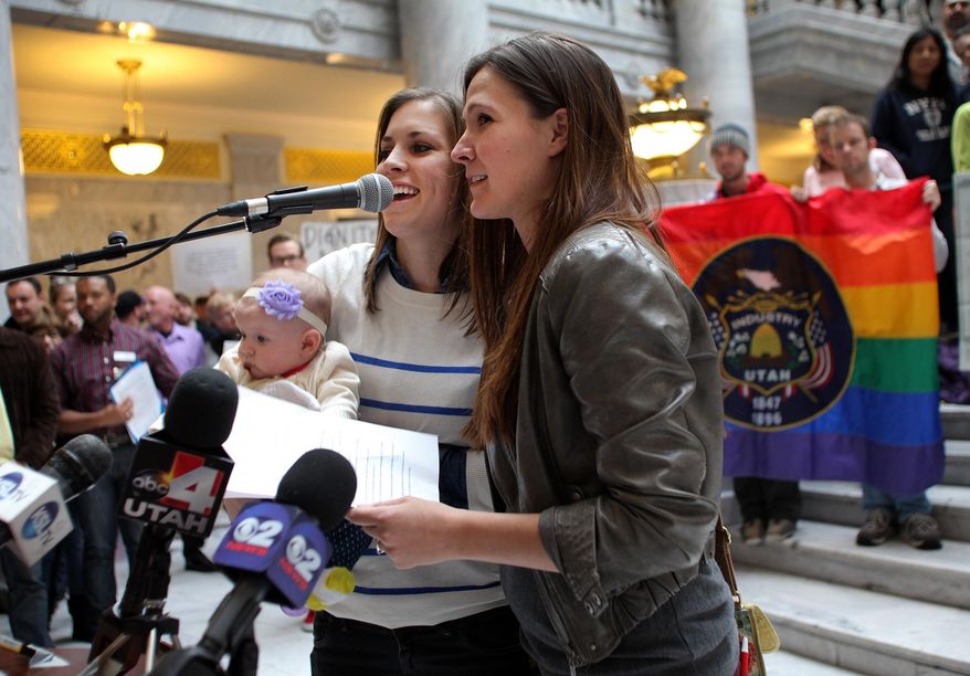 Megan, left, and Candace Berrett, right, hold their daughter Quinn as they speak to supporters of gay marriage during a rally at the Utah State Capitol Friday, Jan. 10, 2014 in Salt Lake City. Supporters of gay marriage filled the rotunda for a rally and to deliver a petition with over 58,000 signatures in support of gay marriage to Utah Governor Gary Herbert. (AP Photo/Steve C. Wilson)